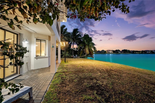 yard at dusk featuring a water view