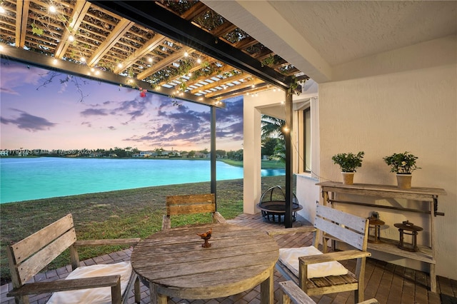 view of patio with a water view, outdoor dining space, a pergola, and an outdoor fire pit