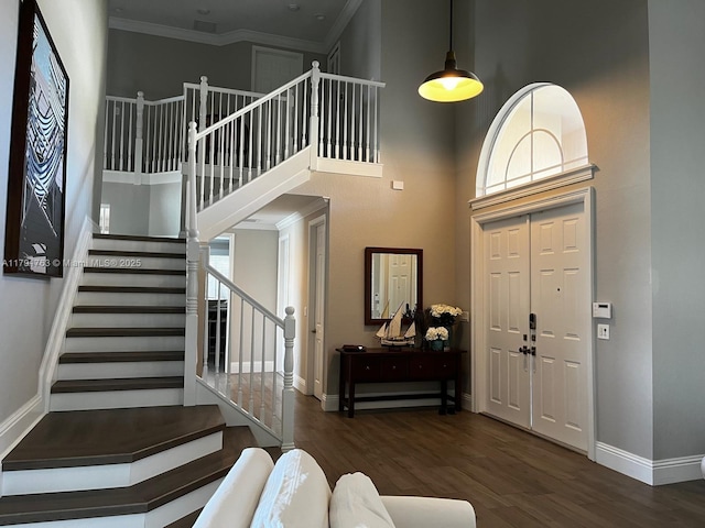 foyer entrance featuring baseboards, wood finished floors, and a towering ceiling