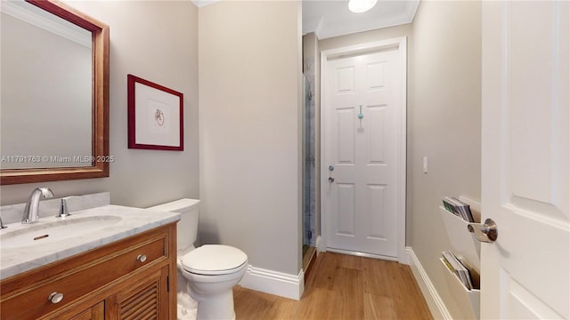 bathroom featuring vanity, toilet, baseboards, wood finished floors, and a stall shower