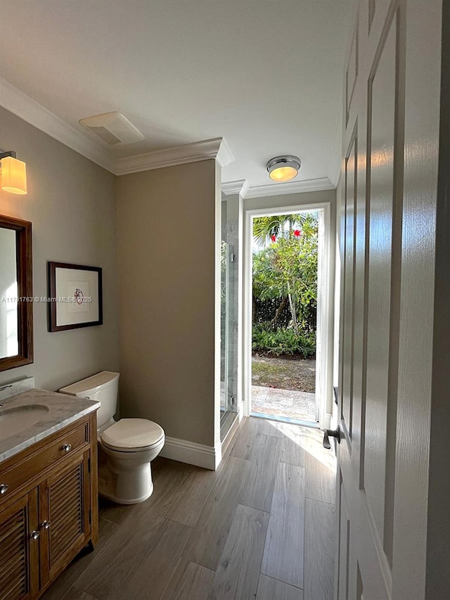 full bath featuring crown molding, vanity, baseboards, wood finished floors, and a stall shower