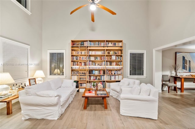 sitting room with wood finished floors, ceiling fan, and a high ceiling