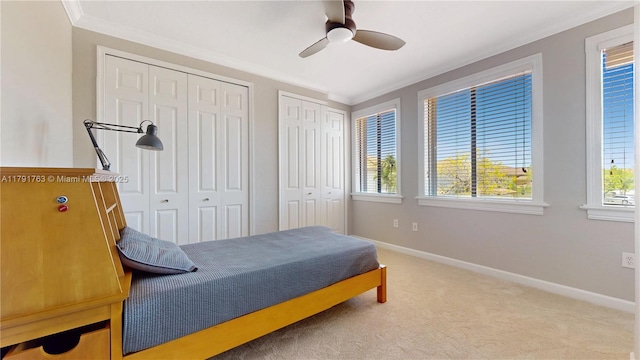 bedroom with baseboards, ornamental molding, multiple closets, and multiple windows