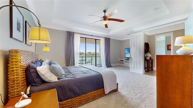 carpeted bedroom featuring a raised ceiling, ceiling fan, and access to exterior