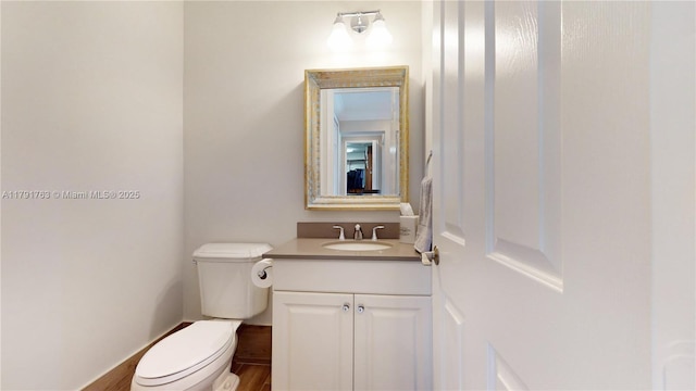 half bathroom featuring vanity, toilet, and wood finished floors