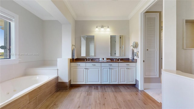 full bath featuring a sink, ornamental molding, a closet, and a garden tub