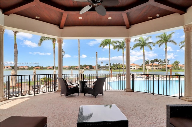 view of patio / terrace with a ceiling fan, a water view, and a swimming pool