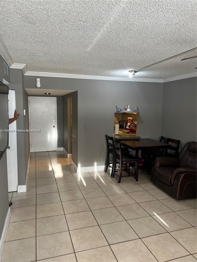 dining area featuring crown molding, light tile patterned floors, and a textured ceiling
