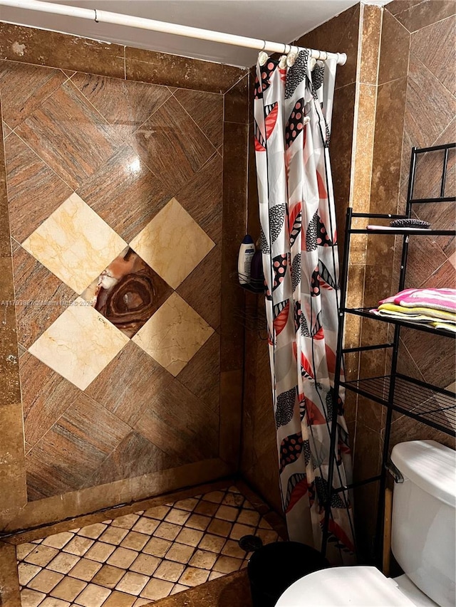 bathroom with a tile shower and toilet