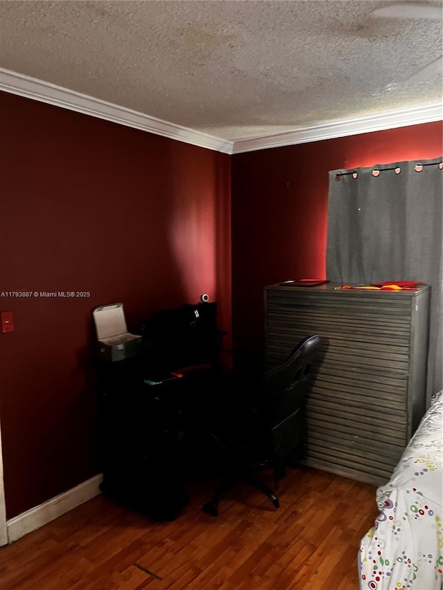 bedroom with baseboards, a textured ceiling, ornamental molding, and wood finished floors