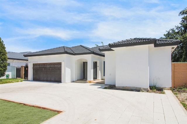 view of front of home featuring stucco siding, an attached garage, driveway, and a tile roof