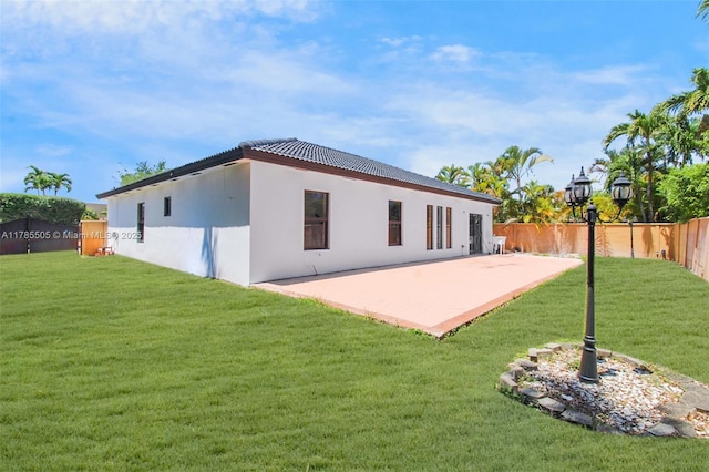 back of property featuring a yard, a tile roof, a fenced backyard, and a patio area