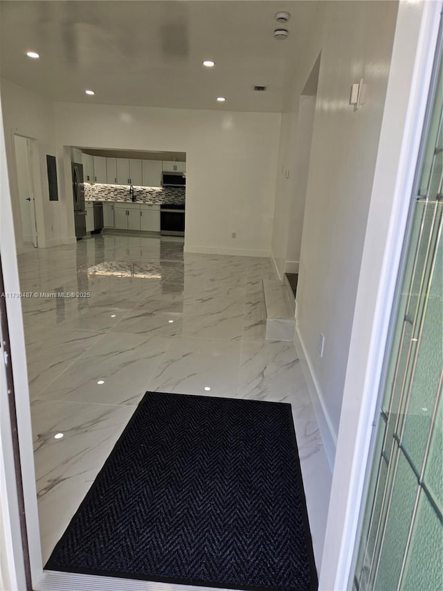 hall with a sink, marble finish floor, recessed lighting, baseboards, and visible vents