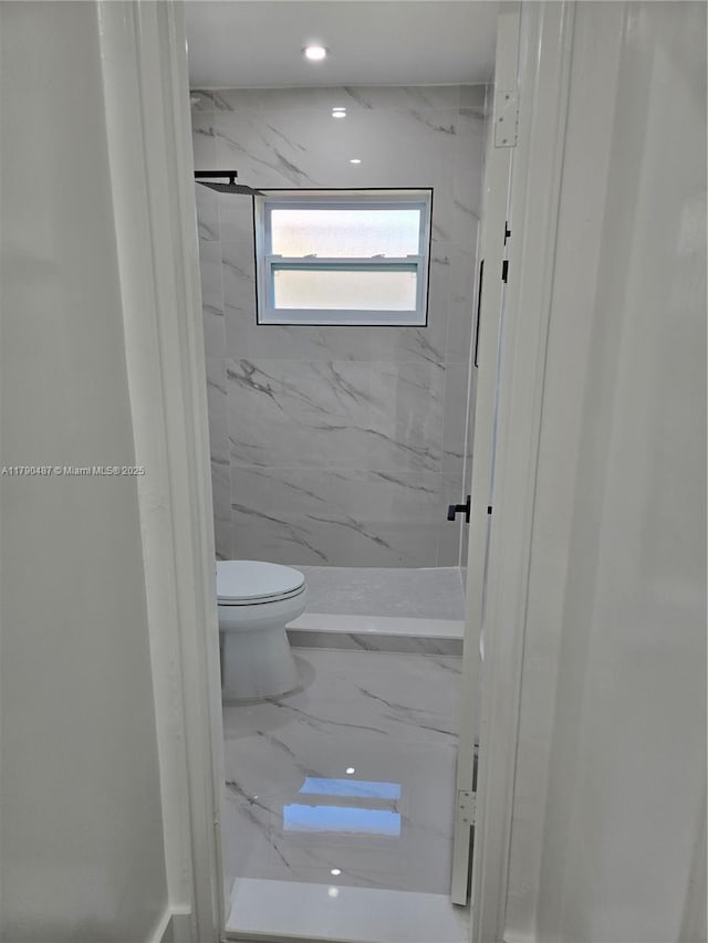 bathroom featuring toilet and a marble finish shower