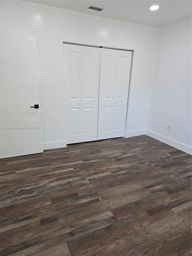 unfurnished bedroom featuring dark wood finished floors, recessed lighting, baseboards, visible vents, and a closet