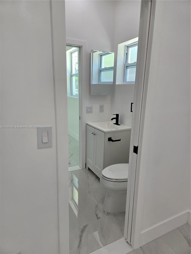 bathroom featuring baseboards, marble finish floor, toilet, and vanity