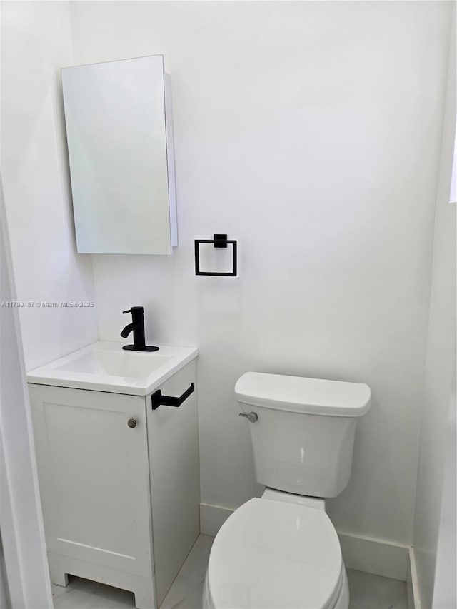 half bath with vanity, baseboards, and toilet
