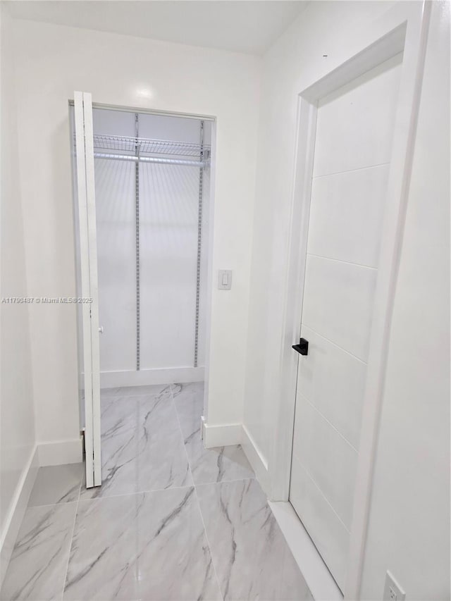 hall with baseboards and marble finish floor