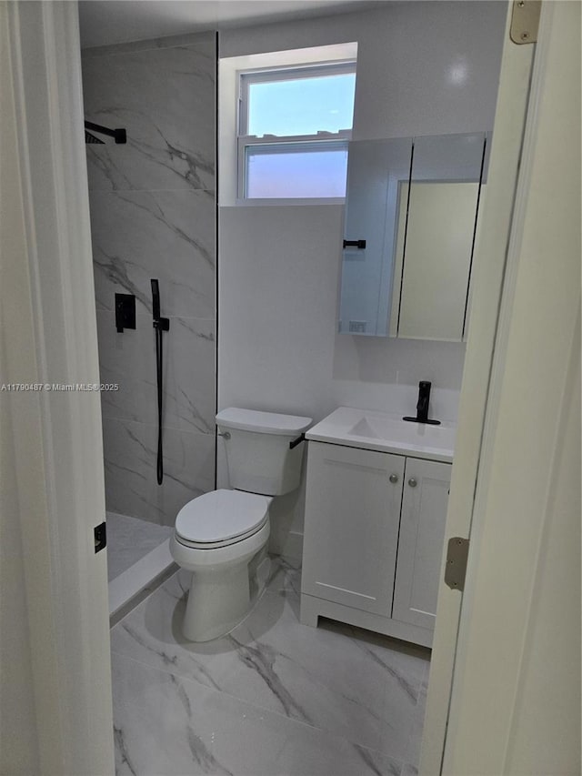 full bathroom featuring toilet, a marble finish shower, marble finish floor, and vanity