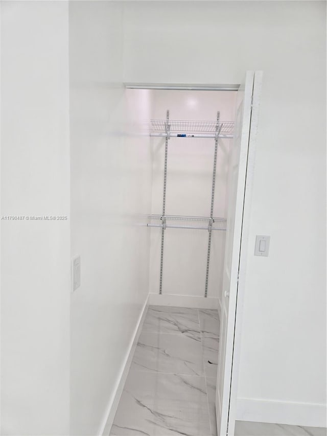 walk in closet with marble finish floor