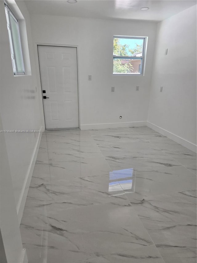 spare room with baseboards and marble finish floor