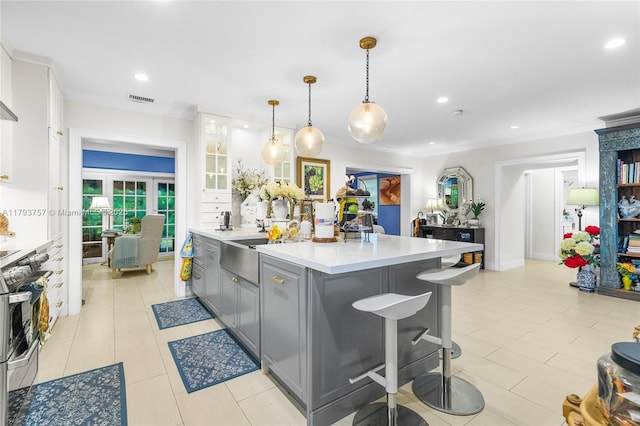 kitchen featuring crown molding, stainless steel stove, light countertops, gray cabinets, and visible vents