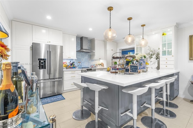 kitchen featuring decorative backsplash, a kitchen breakfast bar, wall chimney range hood, white cabinets, and high end refrigerator