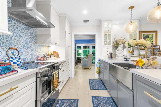 kitchen featuring visible vents, decorative backsplash, stainless steel range with electric stovetop, wall chimney range hood, and a sink