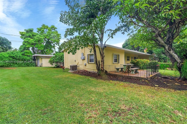 back of property featuring a lawn, a wooden deck, stucco siding, and central AC