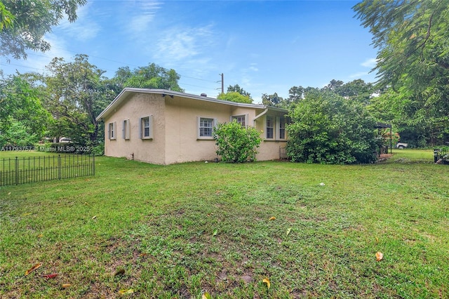 view of property exterior with fence, stucco siding, and a yard