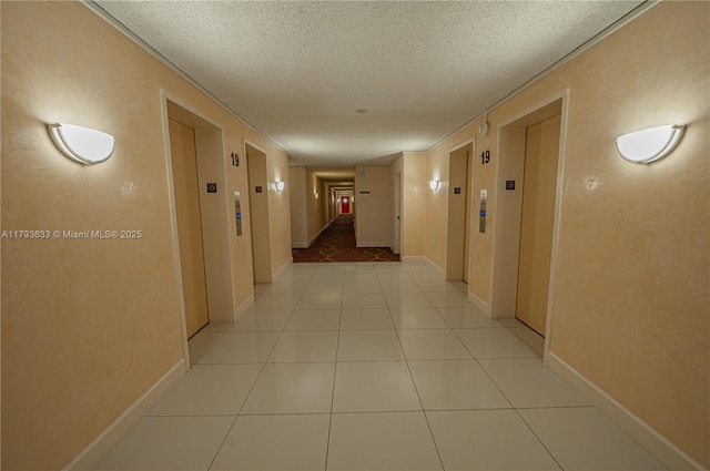 hallway with light tile patterned floors, elevator, and a textured ceiling