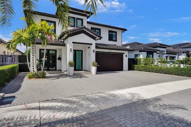 view of front of house featuring a garage, decorative driveway, stucco siding, and french doors