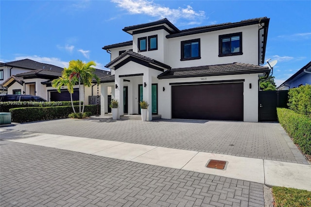view of front of house with fence, decorative driveway, stucco siding, a tiled roof, and an attached garage