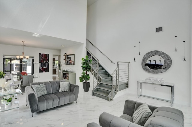 living area with stairs, visible vents, an inviting chandelier, and marble finish floor