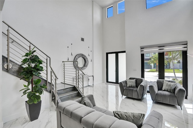 living room with a high ceiling, french doors, marble finish floor, baseboards, and stairway