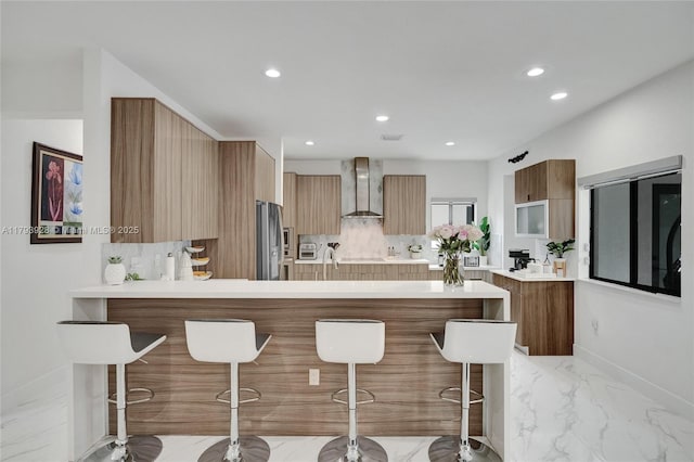 kitchen featuring a breakfast bar area, stainless steel fridge with ice dispenser, modern cabinets, and wall chimney exhaust hood