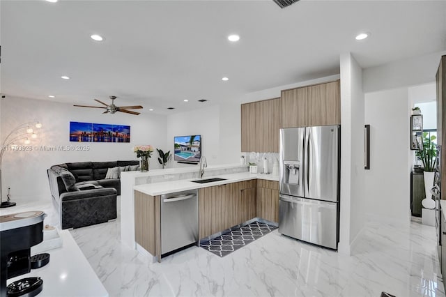 kitchen featuring ceiling fan, appliances with stainless steel finishes, modern cabinets, a sink, and light countertops
