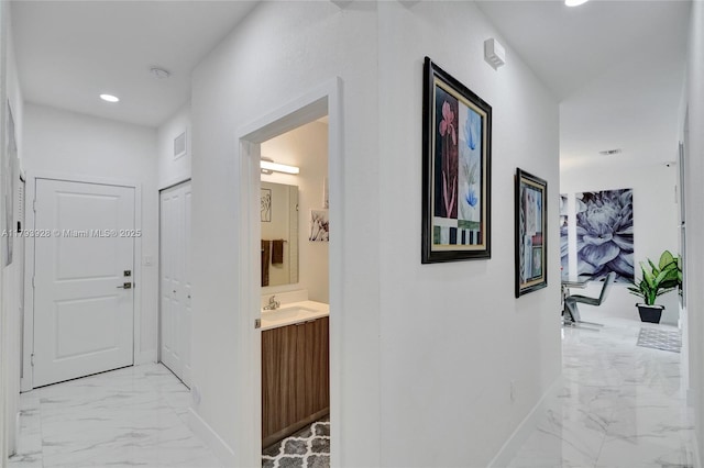 hall featuring visible vents, marble finish floor, baseboards, recessed lighting, and a sink