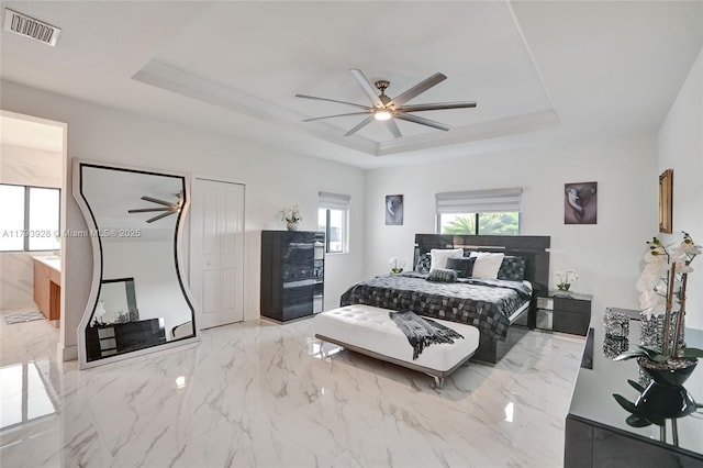 bedroom with marble finish floor, ceiling fan, visible vents, and a raised ceiling