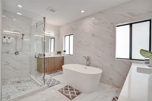 bathroom with a freestanding tub, vanity, stone wall, marble finish floor, and a marble finish shower