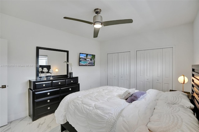 bedroom featuring ceiling fan, two closets, and marble finish floor