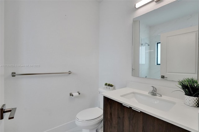bathroom with vanity, baseboards, walk in shower, and toilet