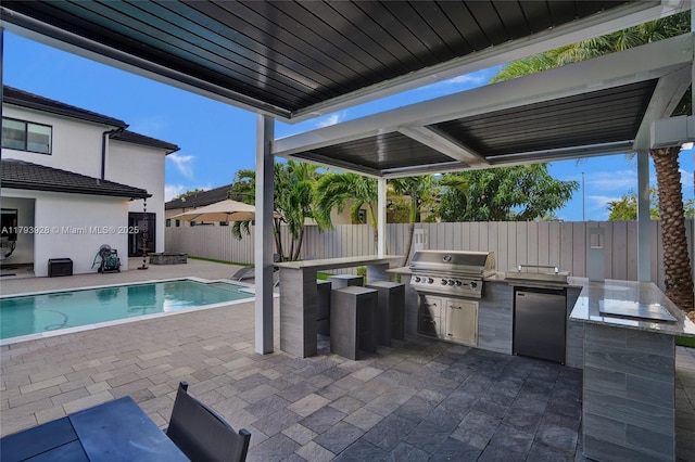 view of patio / terrace featuring an outdoor kitchen, a fenced in pool, a fenced backyard, and area for grilling