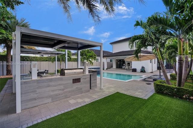 view of pool with fence, a patio, an outdoor kitchen, a fenced in pool, and a lawn