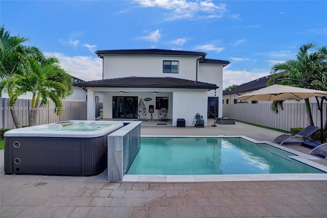 back of house with a fenced backyard, an outdoor hot tub, a patio, and ceiling fan