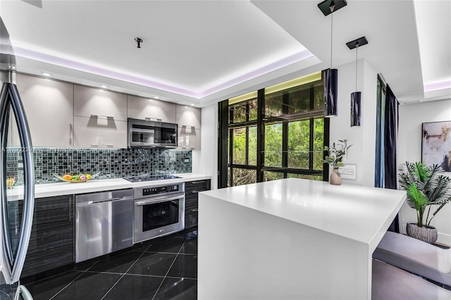 kitchen with a tray ceiling, decorative backsplash, modern cabinets, light countertops, and stainless steel appliances
