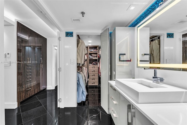 bathroom featuring visible vents, granite finish floor, a spacious closet, and vanity