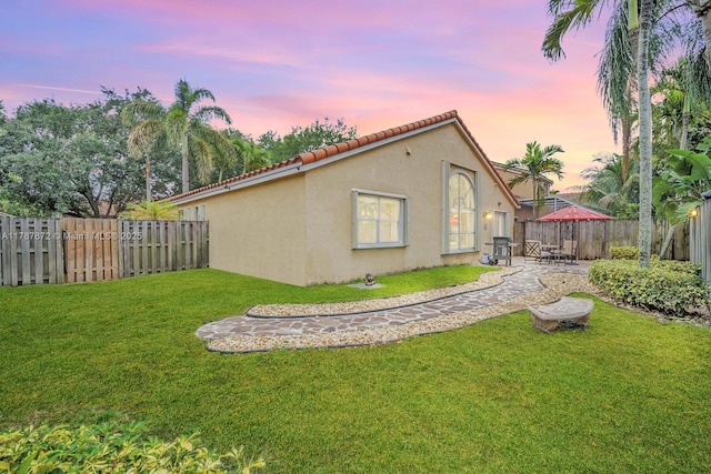 2724 Cayenne Ave, Cooper City, FL 33026 - back of house at dusk with a tile roof, stucco siding, a fenced backyard, a patio area, and a yard