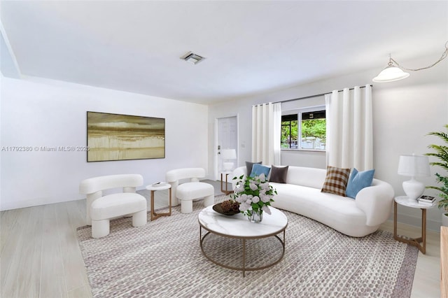 living area with baseboards, visible vents, and wood finished floors