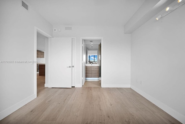 650 NE 32nd St Unit 1004, Miami, FL 33137 - unfurnished bedroom with connected bathroom, baseboards, visible vents, and wood finished floors